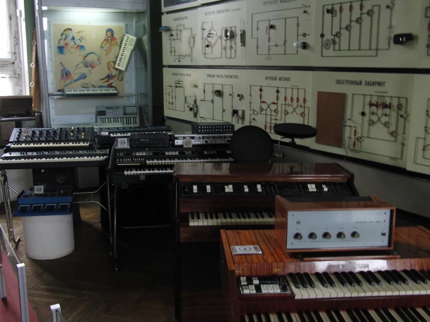 A room in the Polytechnical Museum in Moscow with Soviet keyboards, organs and synthesizers arranged in front of wall panels of circuit diagrams.